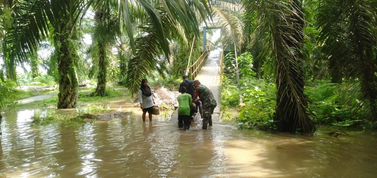 Sertu pajri Maulana turun ke lapangan guna bantu Warga yang melintasi di jalan kelurahan Muara Lakitan