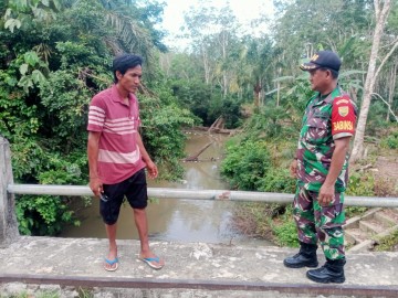M Daud Babinsa Koramil 406-07/Jayaloka Bersama Mitra Karib Babinsa Pantau Wilayah Rawan Banjir di Sungai Temelat Desa Sukakarya